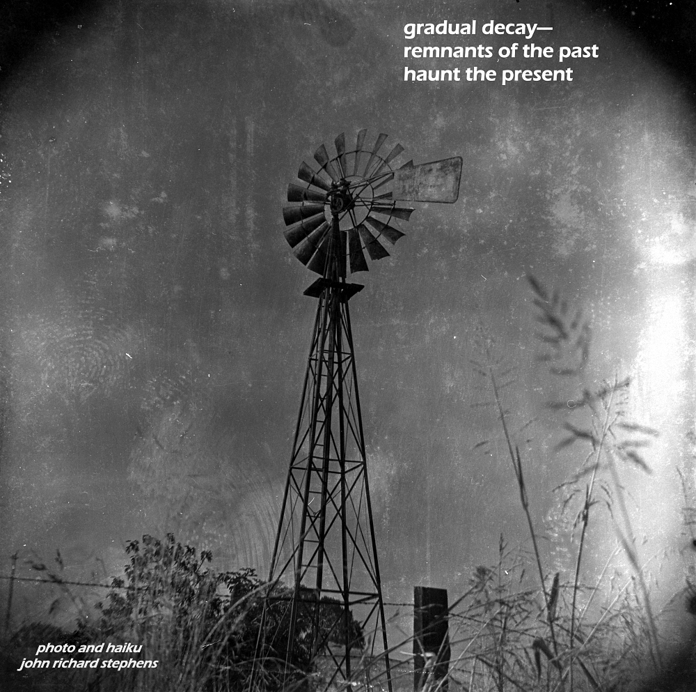 A photo haiku with a black and white photograph of a very old windmill that had been used for drawing up water for cattle. The image is stained and degraded.